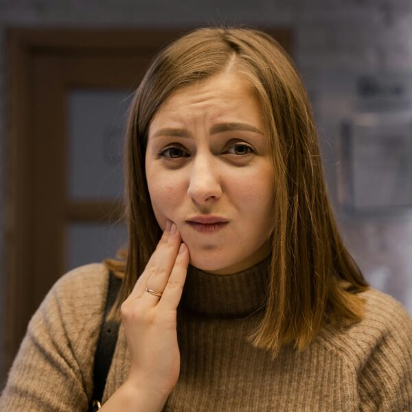 mulher com a mão no rosto demonstrando dor de dente