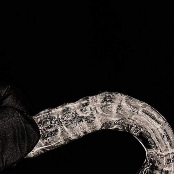 Placa de Bruxismo sendo segurada por uma mão e luva preta