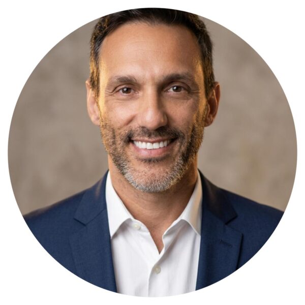 foto do Dr. Claudinei Kochisnki, um homem de pele clara, barba, sorrindo, com cabelos curtos castanhos, vestindo uma camisa branca e um blazer azul.